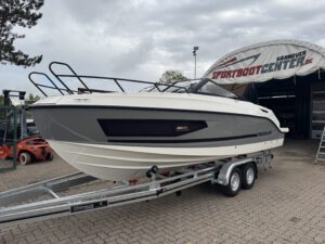 Ein motorisiertes Boot der Marke Quicksilver auf einem Anhänger, im Hintergrund ein Bootszentrum.